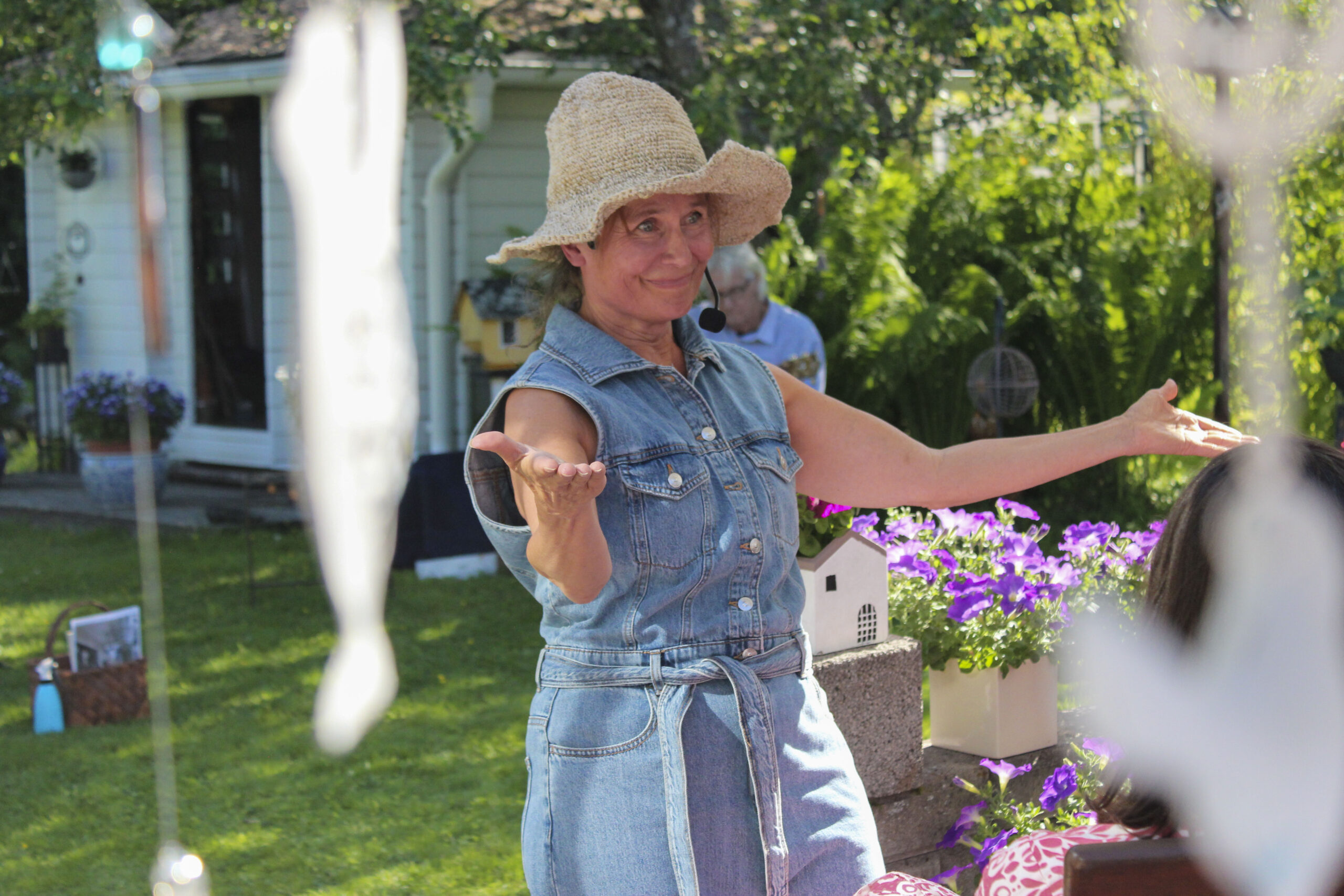 Näyttelijä esiintyy kesäisessä puutarhassa.