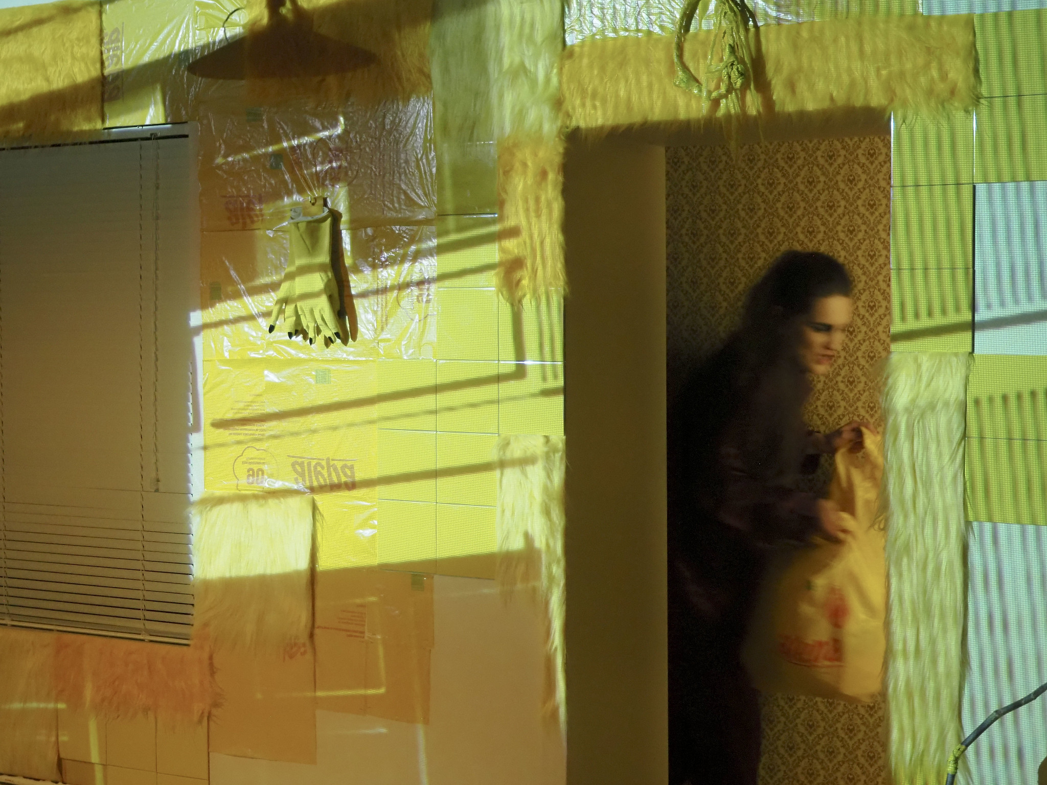 Epätarkka ihmishahmo oviaukossa keltaisissa teatterilavasteissa